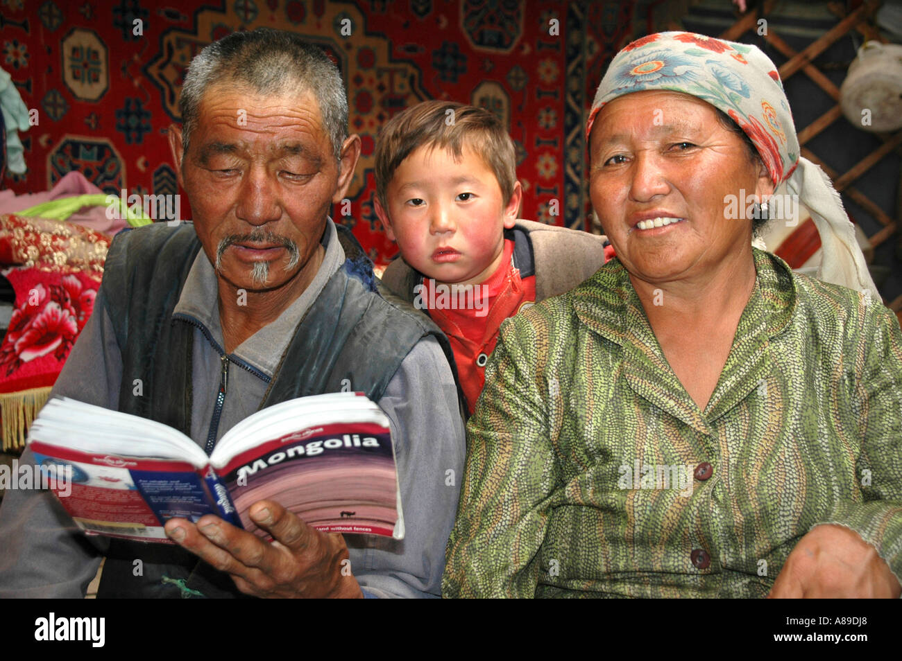Nomaden Mann Frau und Kind sind im Lonely Planet Reiseführer in ihrer Jurte Kharkhiraa mongolischen Altai in der Nähe von Ulaangom lesen. Stockfoto