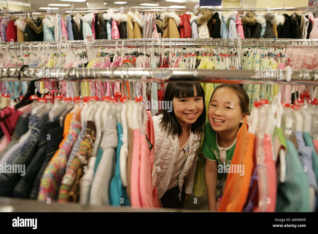 Zwei asiatische Mädchen zwischen einem Rack von Kleidung Stockfoto