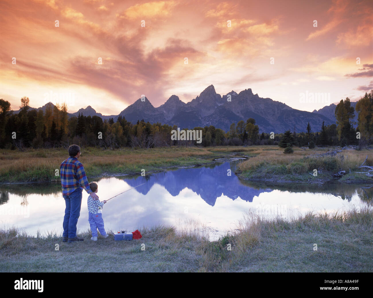 Vater und Sohn Angeln im kleinen See bei Sonnenuntergang unter Grand Teton in der Nähe von Snake River in Wyoming Stockfoto