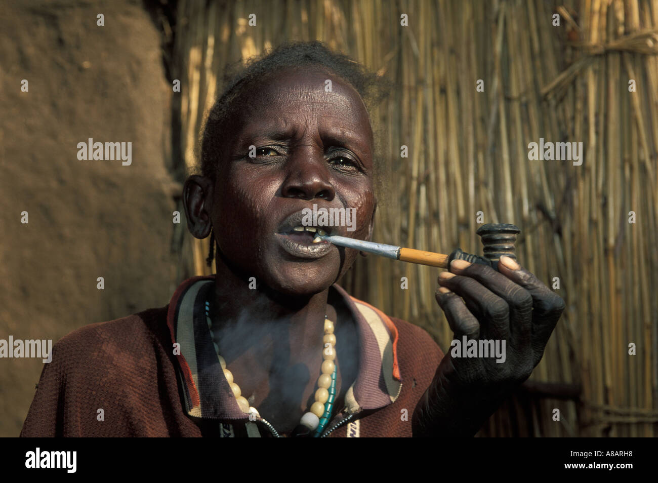 Frau mit traditionellen Gesichts Narbenbildung, raucht eine Pfeife, Gambella, Äthiopien Stockfoto