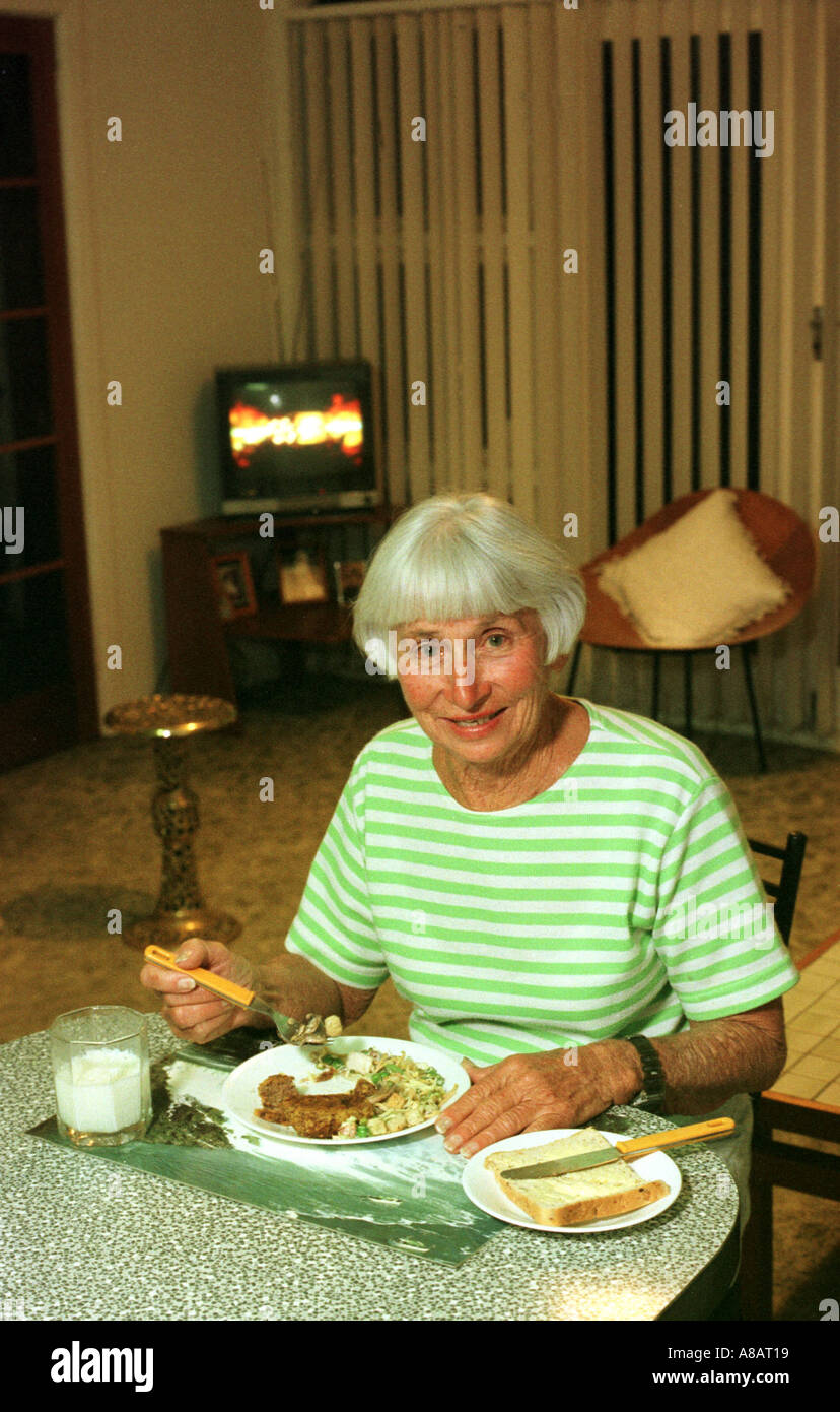 Eine ältere Frau isst ihr Abendessen allein zu Hause Stockfoto
