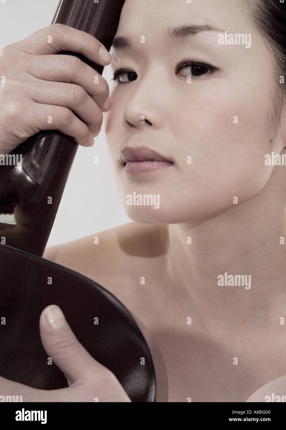 Junge schöne nackte Japanerin in professionellen MakeupHighFashion und hält eine akustische
