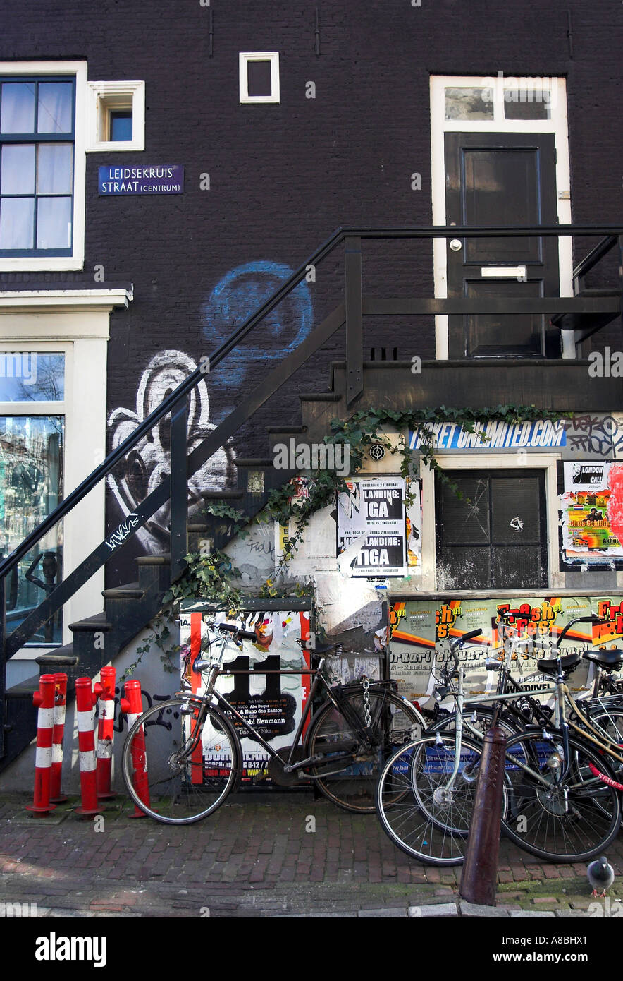 Ein Porträt Format Bild einer typischen inneren Stadt Amsterdam Seitenstraße mit Fahrrädern und Graffitis an den Wänden. Stockfoto