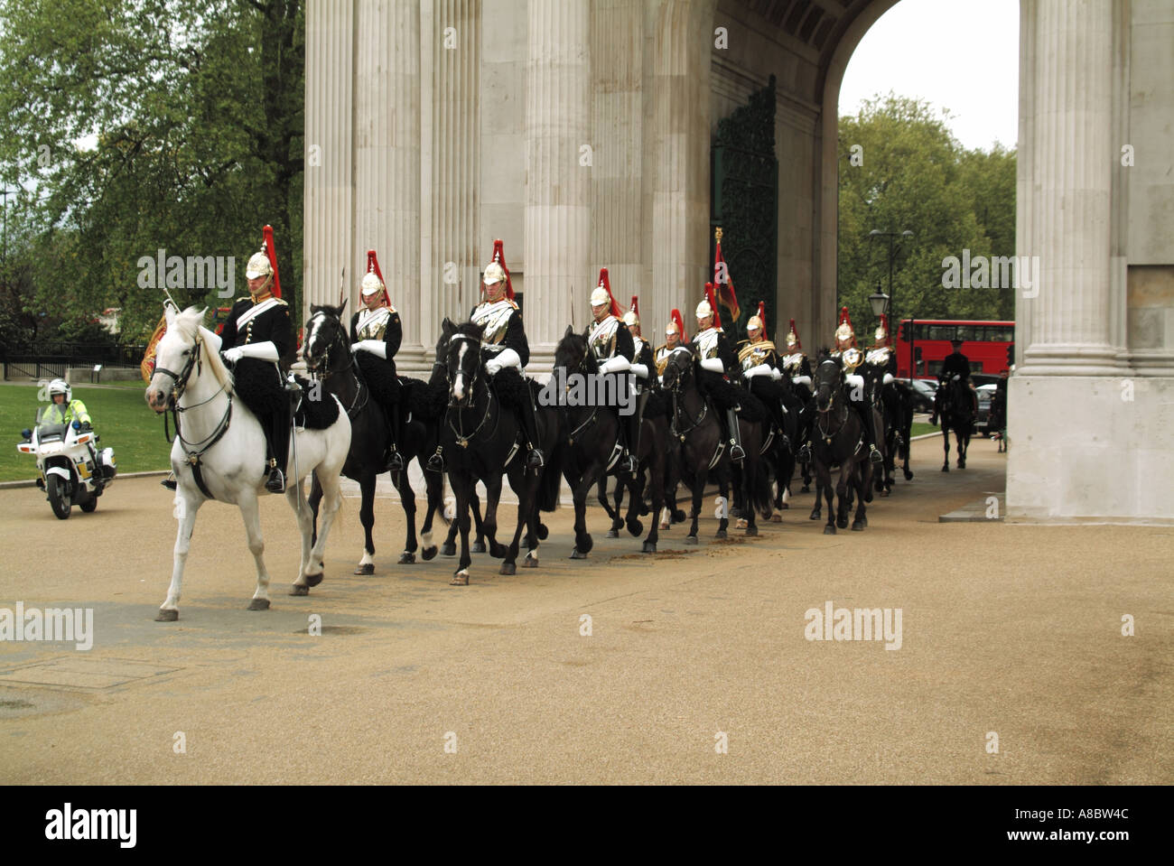 Hyde Park Corner Verfassung Bogen ein Geschwader von The Blues und Royals mit roten und blauen Tuniken Federbusch Helme mit Polizei-Eskorte Stockfoto