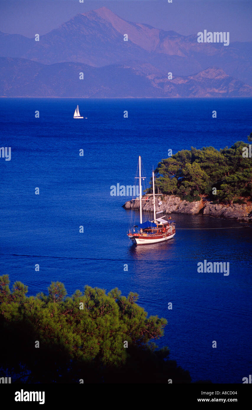 Segelboote und Motorboote vor Anker auf einer Insel und Segelboote im Hintergrund Golf von Fethiye Türkei Stockfoto