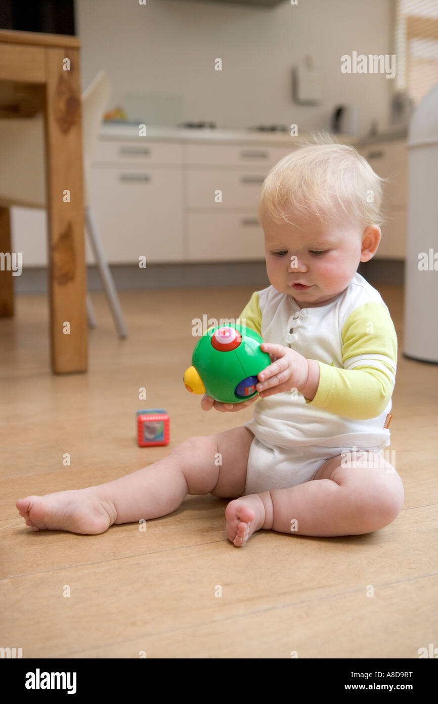 Kind sitzt auf dem Boden mit einem Spielzeug Stockfoto