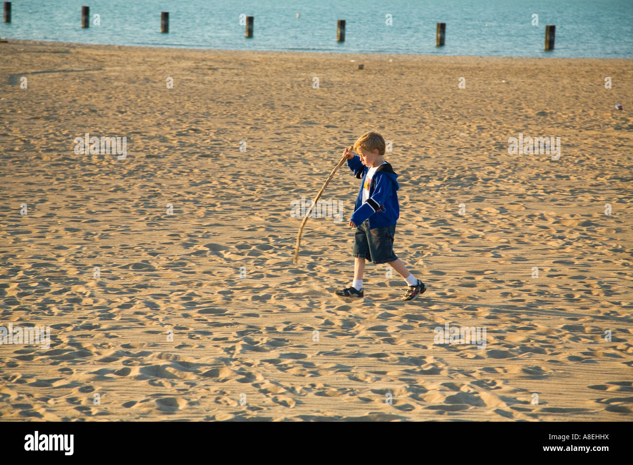 CHICAGO Illinois Young Boy laufen im Sand und Stick Strand entlang Lake Michigan See tragen Stockfoto