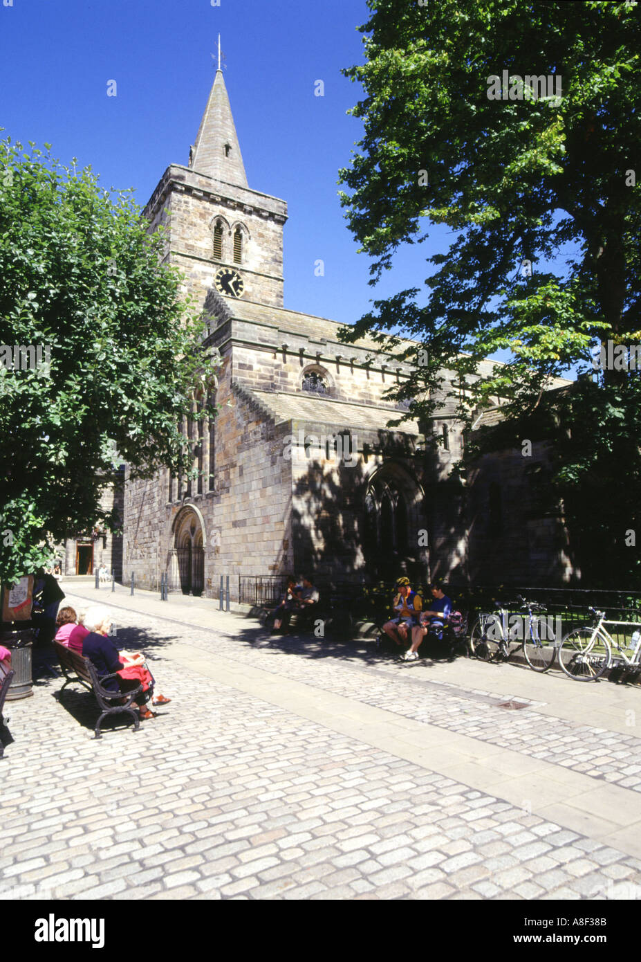 dh ST ANDREWS FIFE Dreifaltigkeitskirche Menschen sitzen der Bank gepflasterten Platz Kirche Stein Stockfoto