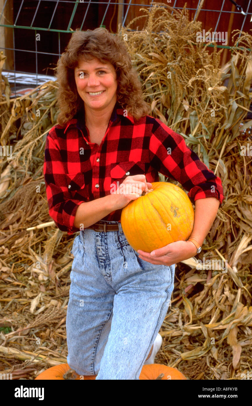 Schöne Frau im karierten Hemd mit Kürbis vor Maisstroh Alter von 30 Jahren. Buffalo-Minnesota-USA Stockfoto