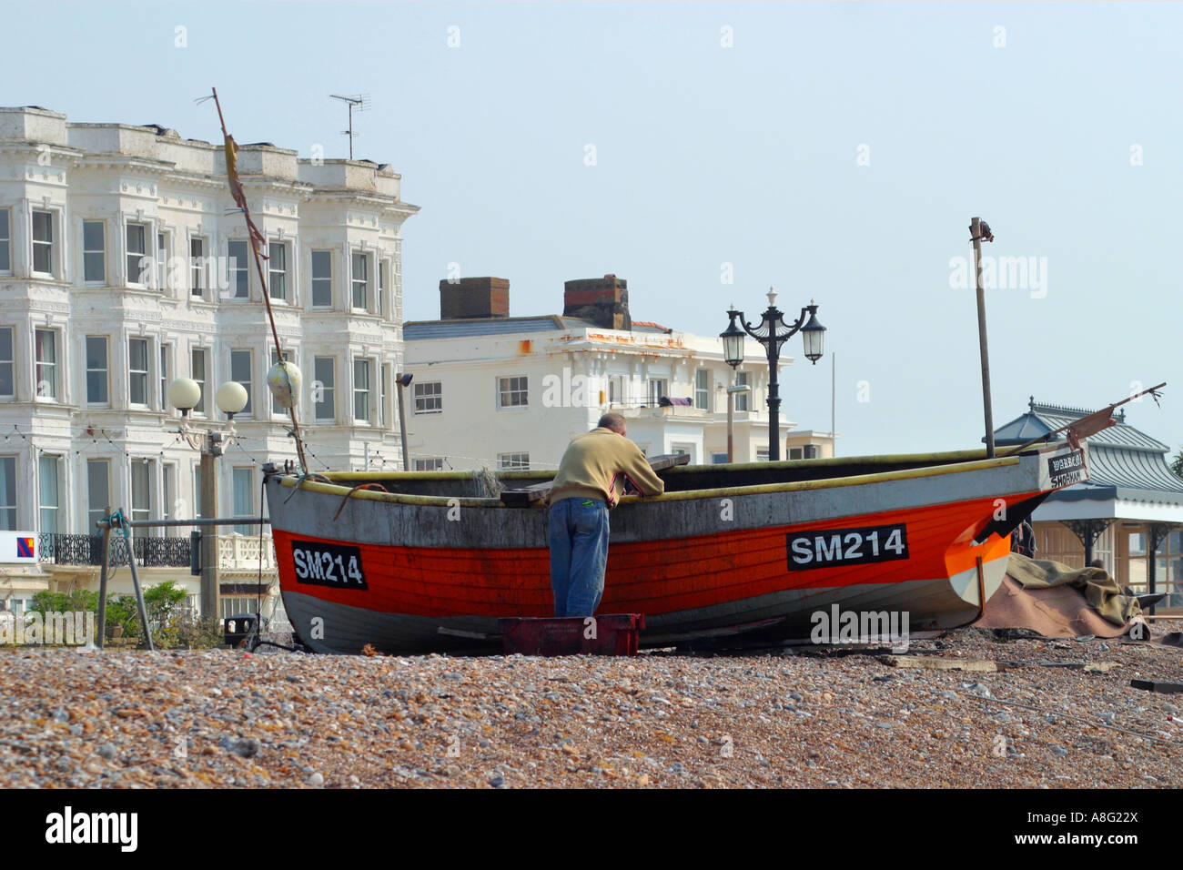 Ein einziger Fischer, der sich am Strand von Worthing, West Sussex, Großbritannien, in sein Boot lehnt Stockfoto