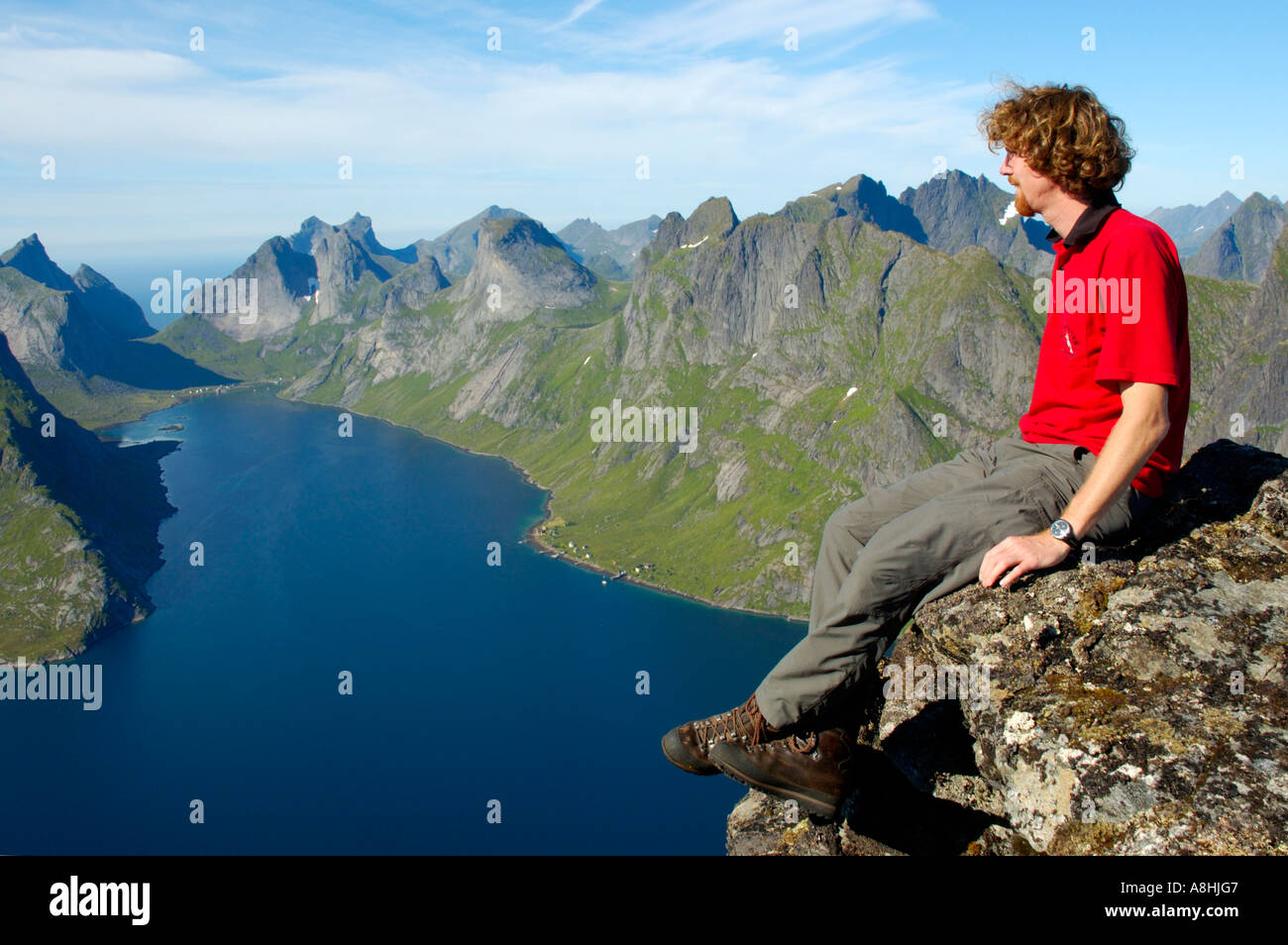 Herr Mountaineerer genießt die grand Aussicht vom Gipfel Navaren auf rauen Bergen mit Fjord Kjerkfjorden Moskenesoya Lofoten Norwegen Stockfoto