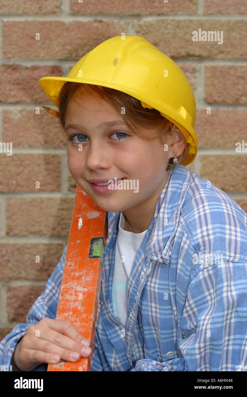 Junges Mädchen gekleidet als Baumeister mit Sicherheit Schutzhelm und Wasserwaage Stockfoto