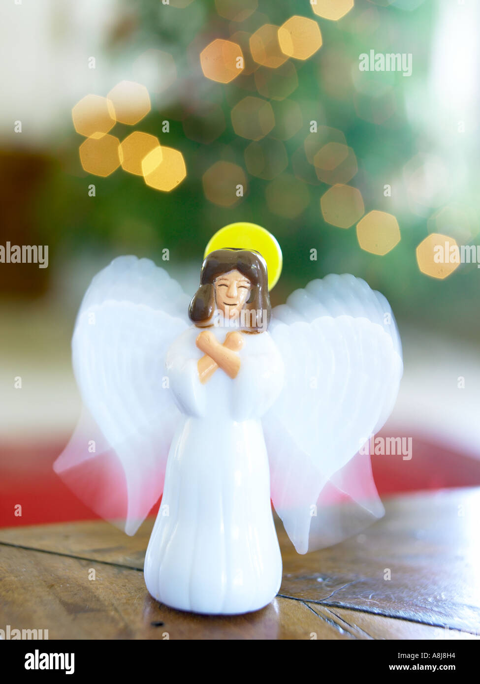 Weißer Kunststoff Engel mit Flügeln infront des Weihnachtsbaums auf Tisch stehend Stockfoto