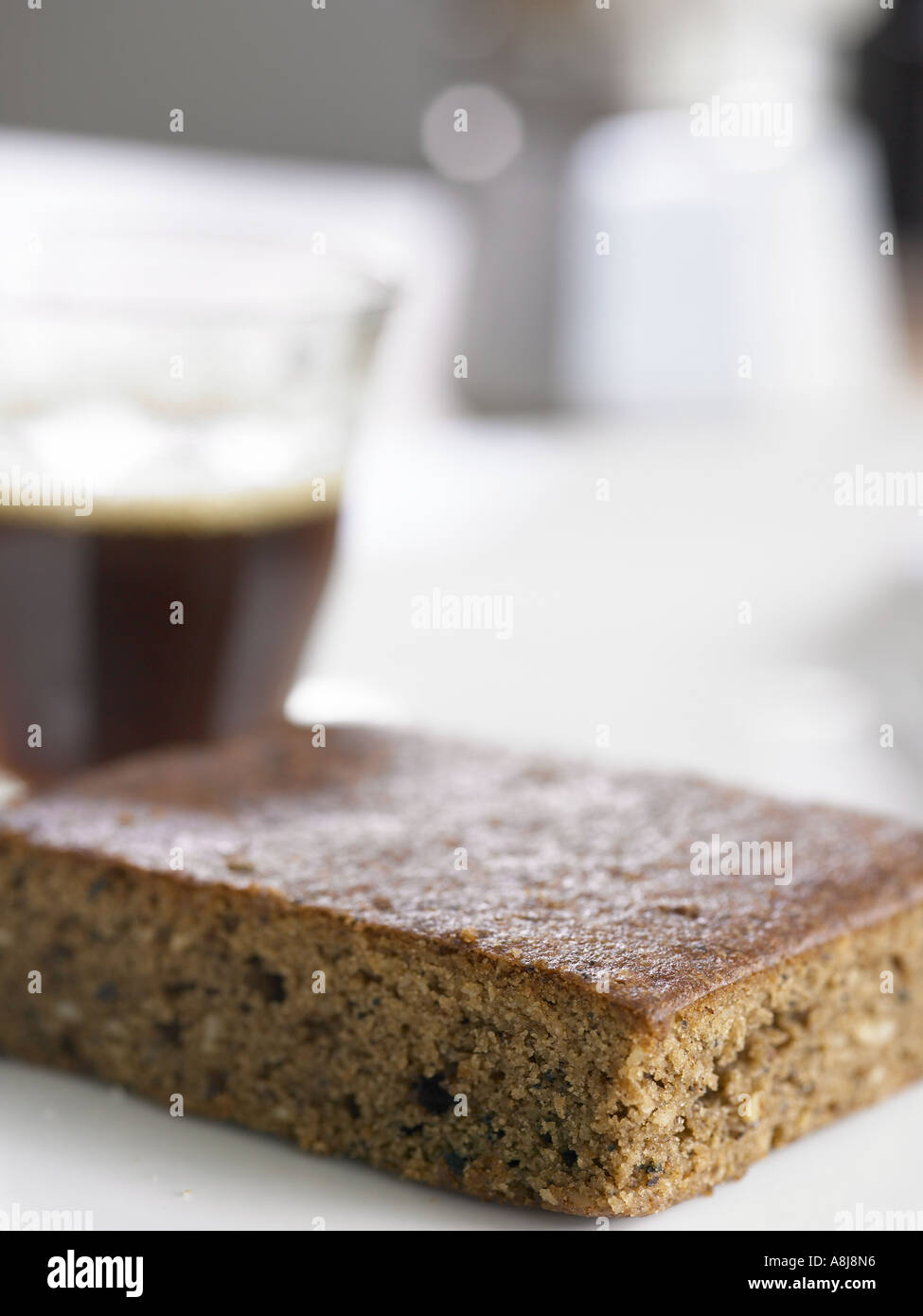 Kaffee-Kuchen-Slice auf Seitenteil mit einer Kaffeemaschine und einem Schuss Espresso im Hintergrund unscharf Stockfoto