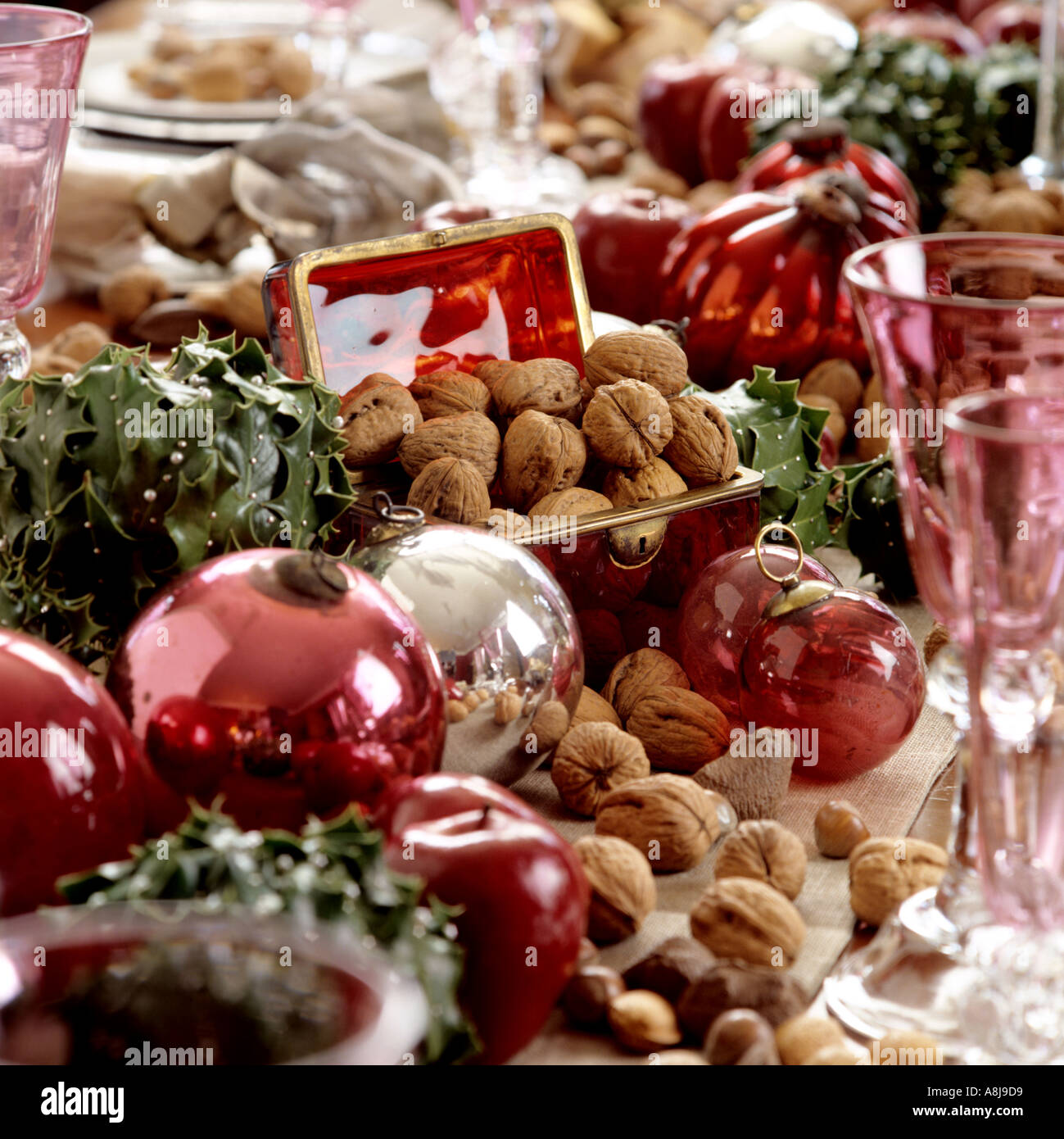 Rosa Kugeln, Nüssen und Glaswaren auf ein Weihnachtstisch Stockfoto