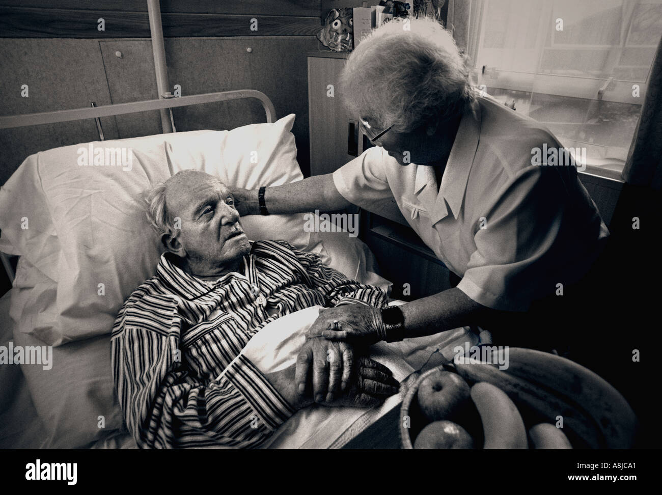 Coronavirus, Der Eine Frau besucht, tröstet den älteren Herrn in seinem Pflegeheim, in dem er schwarz-weiß behandelt wird Stockfoto