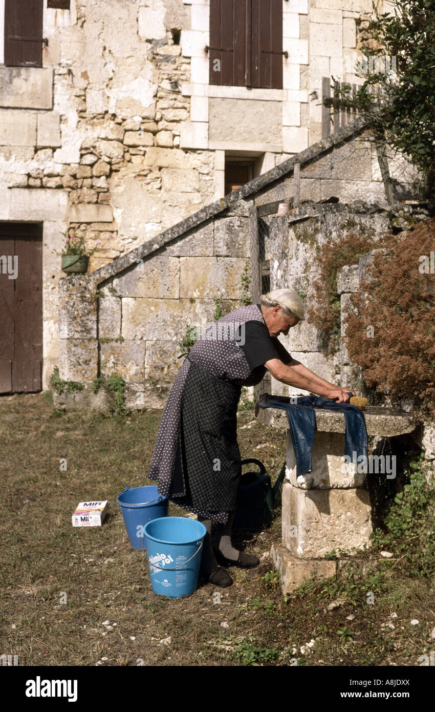 Alte Bäuerin in Nordfrankreich Wäsche draußen aus einem Eimer Stockfoto