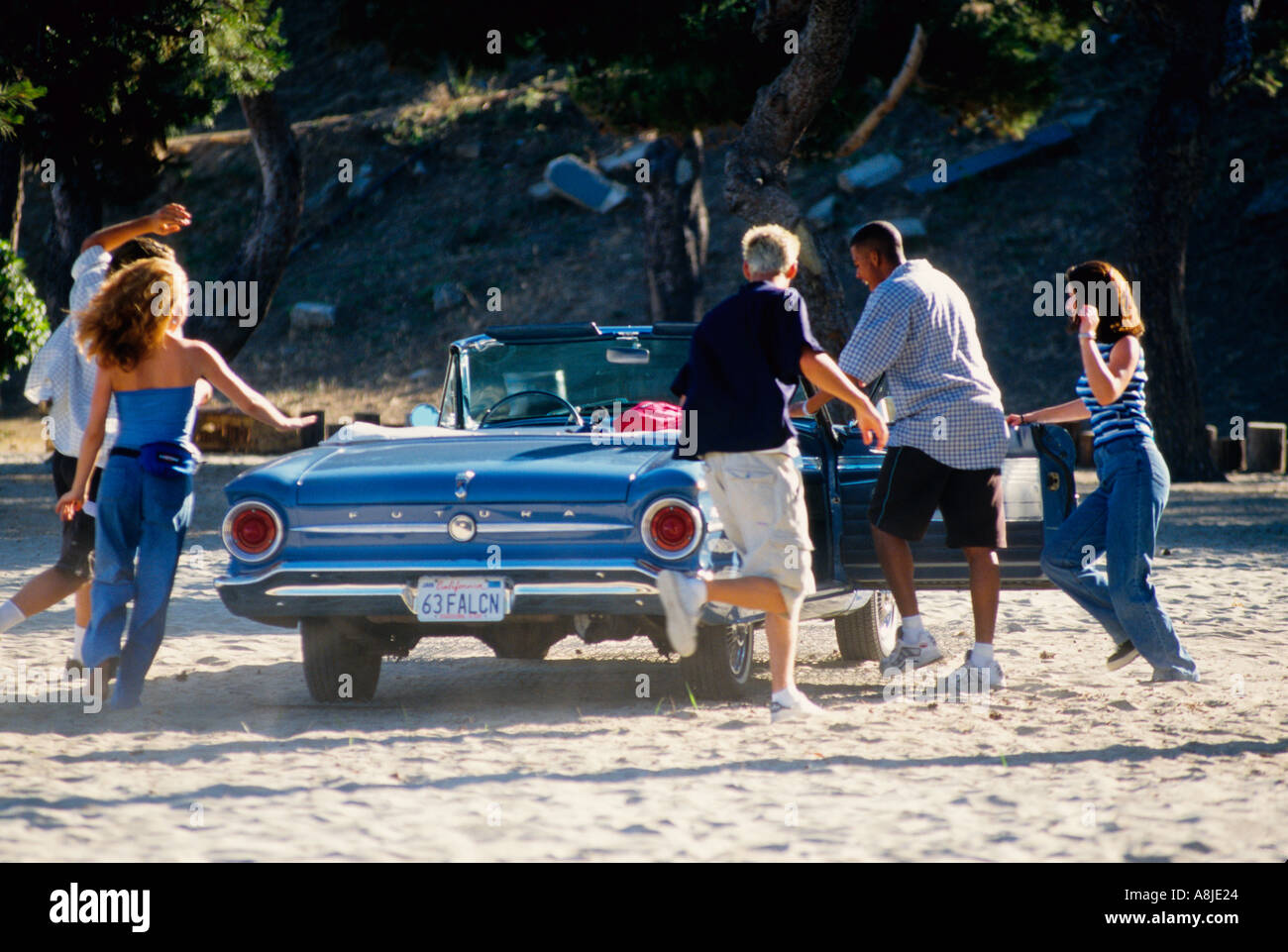 Jugendliche führen zu ihrem Cabrio Auto am Strand Stockfoto