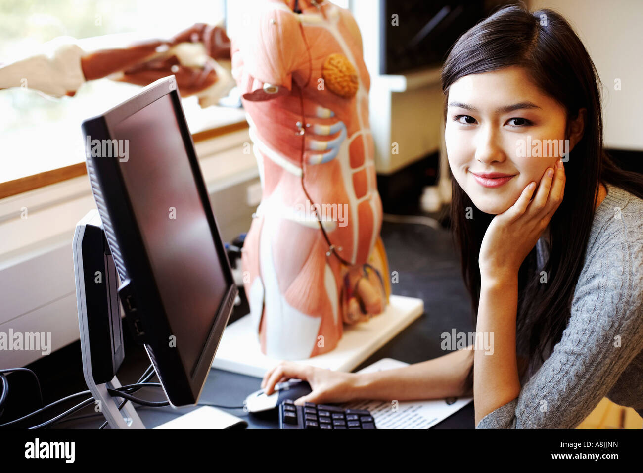 Porträt einer jungen Frau vor einem Computer und ein anatomisches Modell Stockfoto