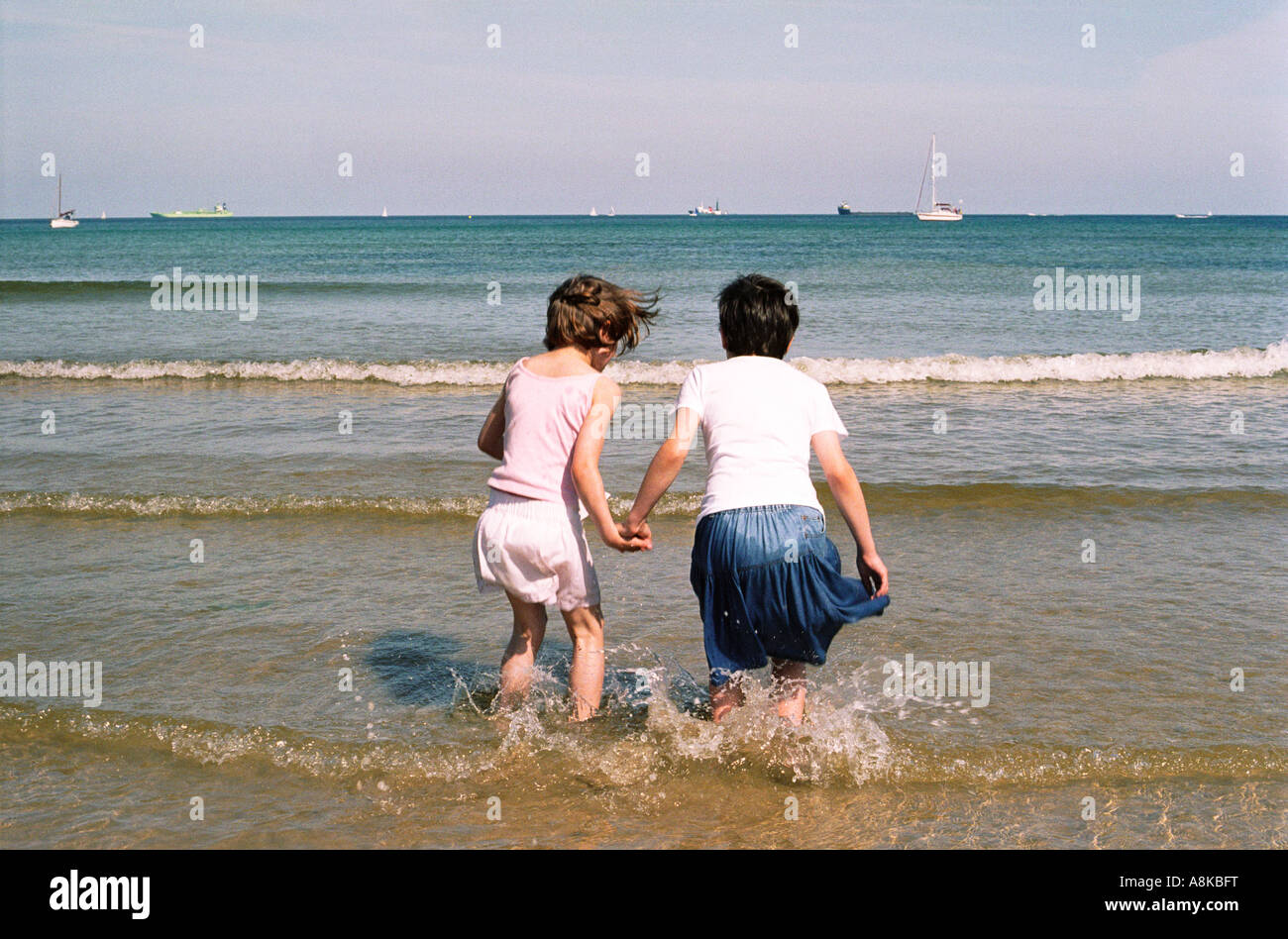 Zwei Kinder hand in hand Wellen springen Stockfoto