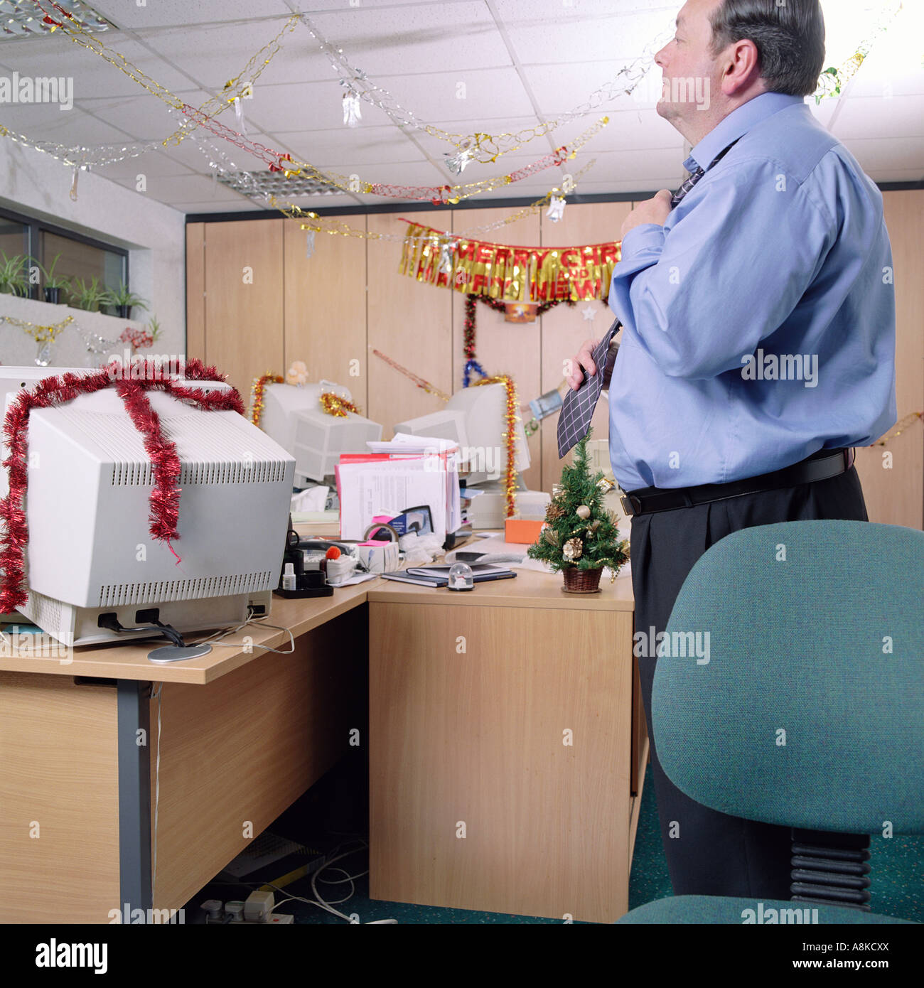 Ein Geschäftsmann stehend in einem Büro, umgeben von Weihnachtsschmuck Stockfoto