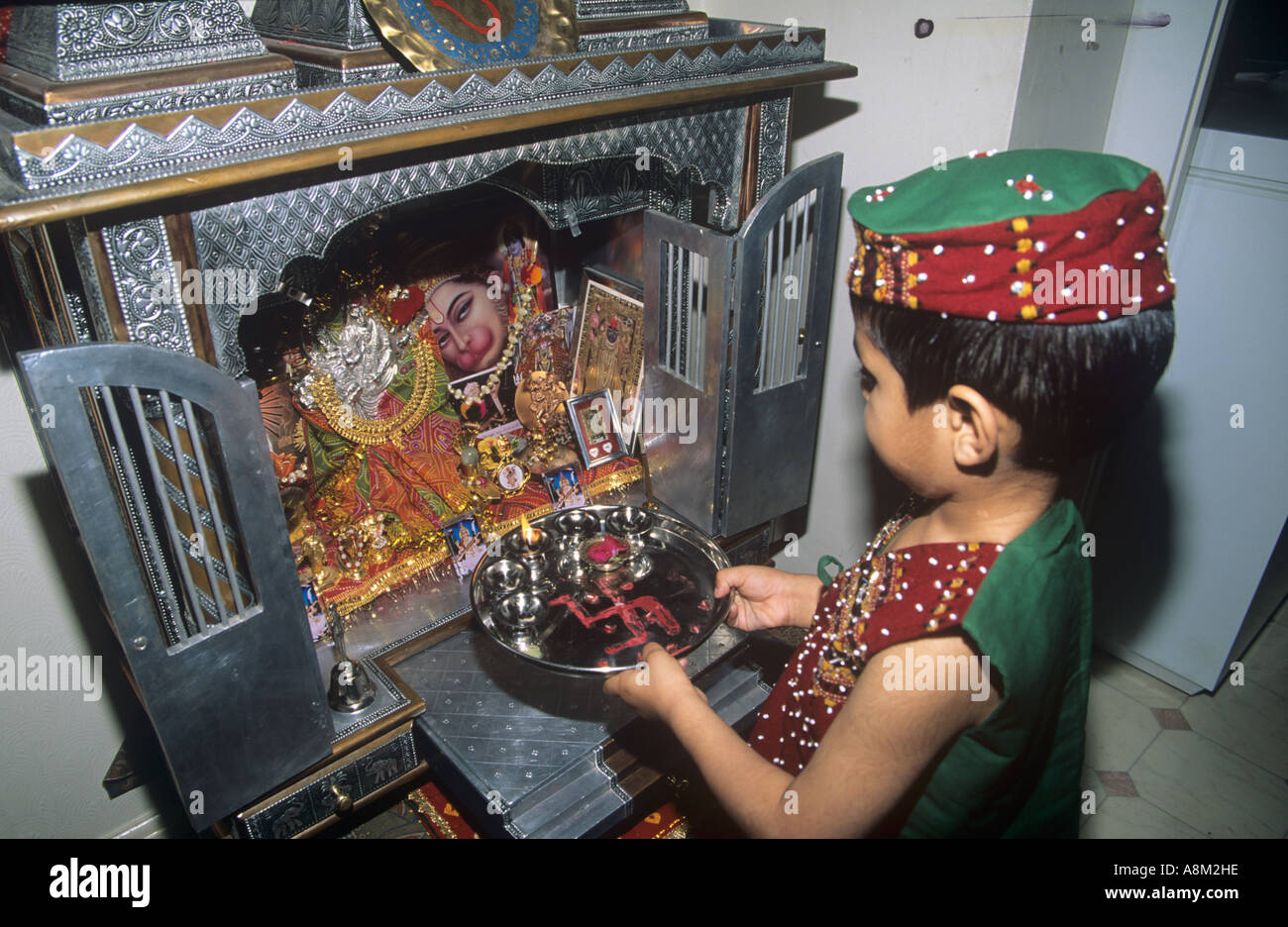 Hindu Kind mit Puja in einem kleinen familiären Mandir oder Schrein Stockfoto