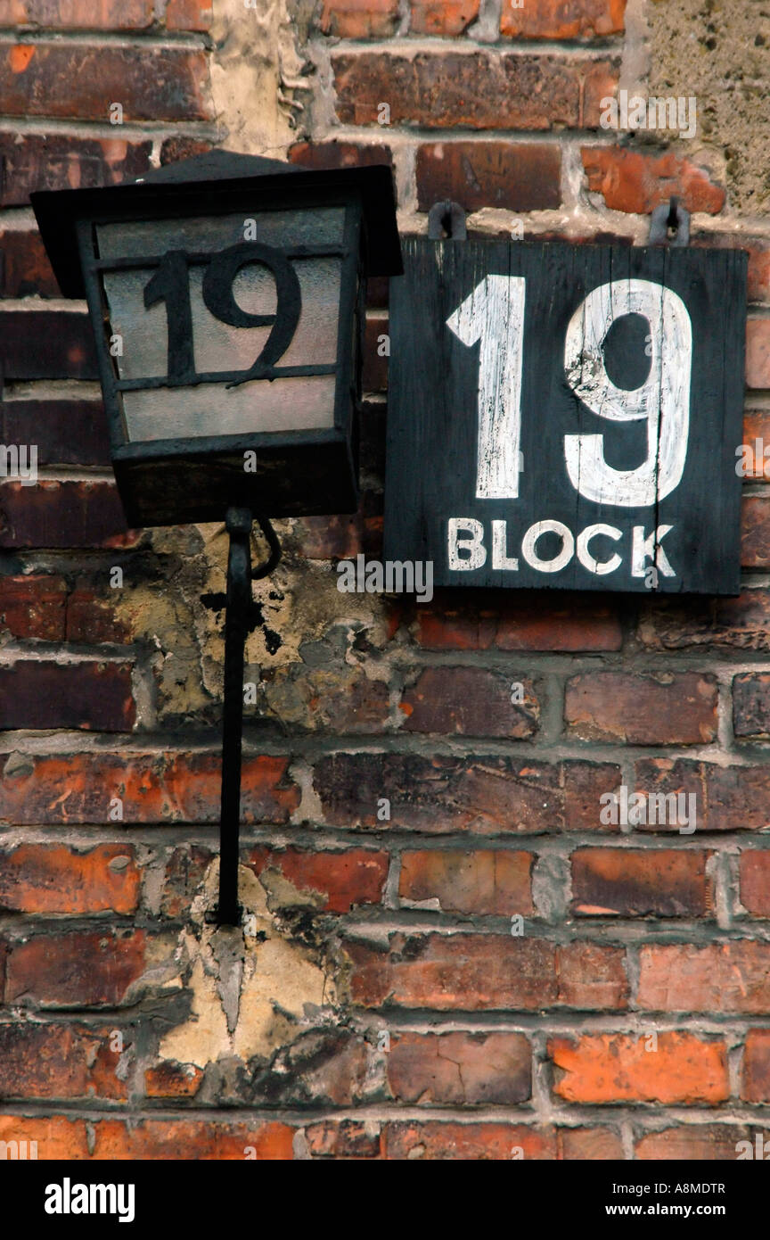 Vertikale Nahaufnahme von schwarzen und weißen Zeichen und alte altmodische Lampe außerhalb Block 19 im KZ Auschwitz. Stockfoto