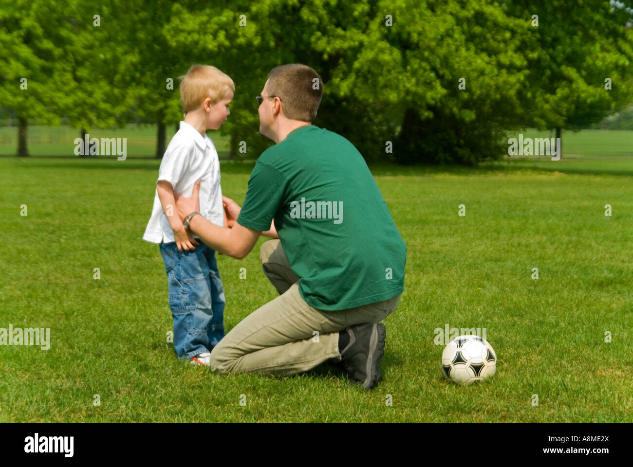 Horizontale Porträt eines jungen Vaters Disziplinierung seinen jungen Sohn während eines Spiels der Fußball im park Stockfoto