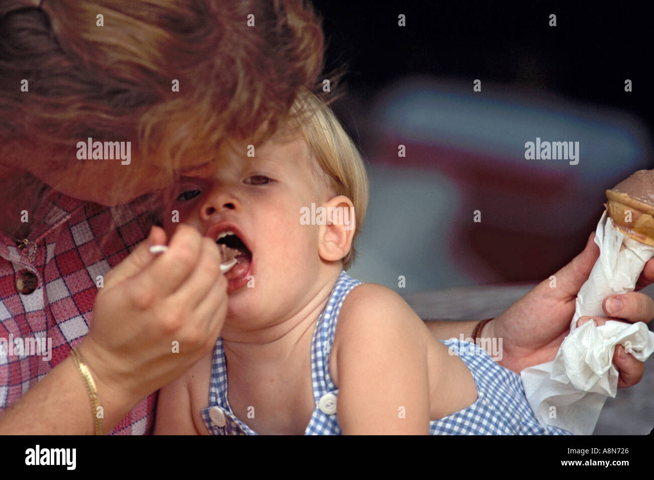 Kind von Löffel von Mom Eis gefüttert Stockfoto