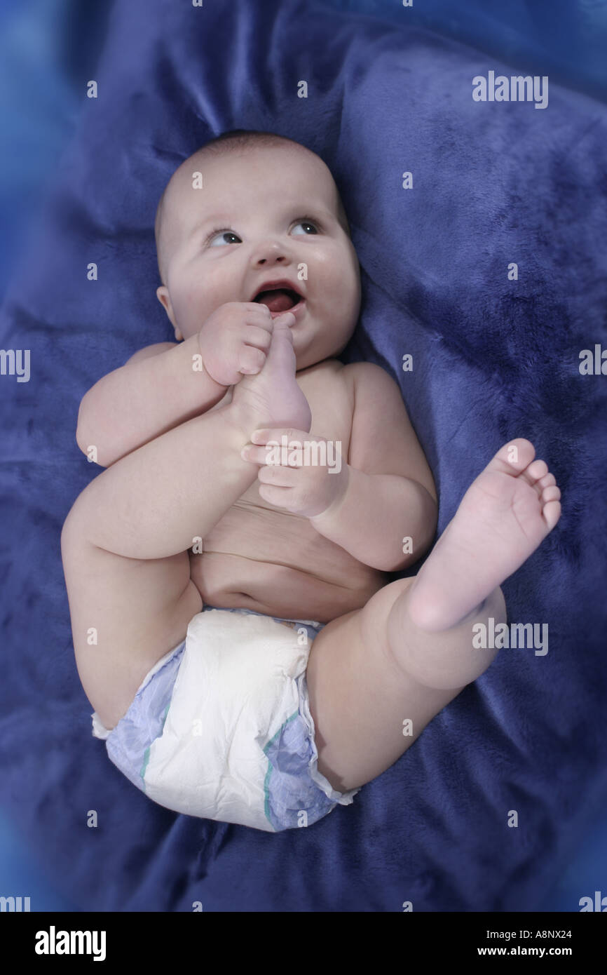Baby Junge Clad In Windel Rollt Freudig Auf Blauen Kissen