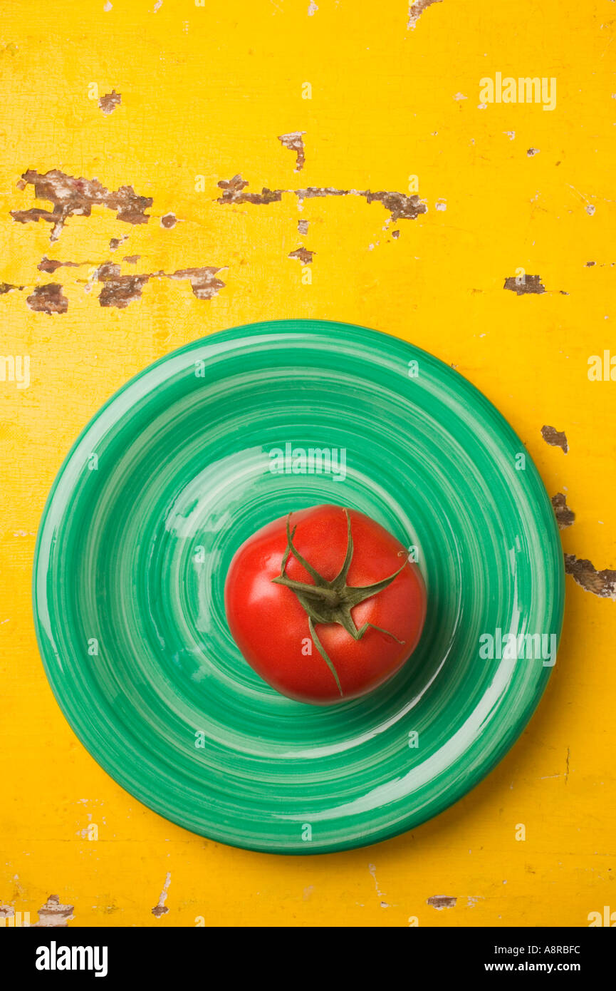 Rote Tomaten auf Teller grün auf gelb Tisch Stockfoto