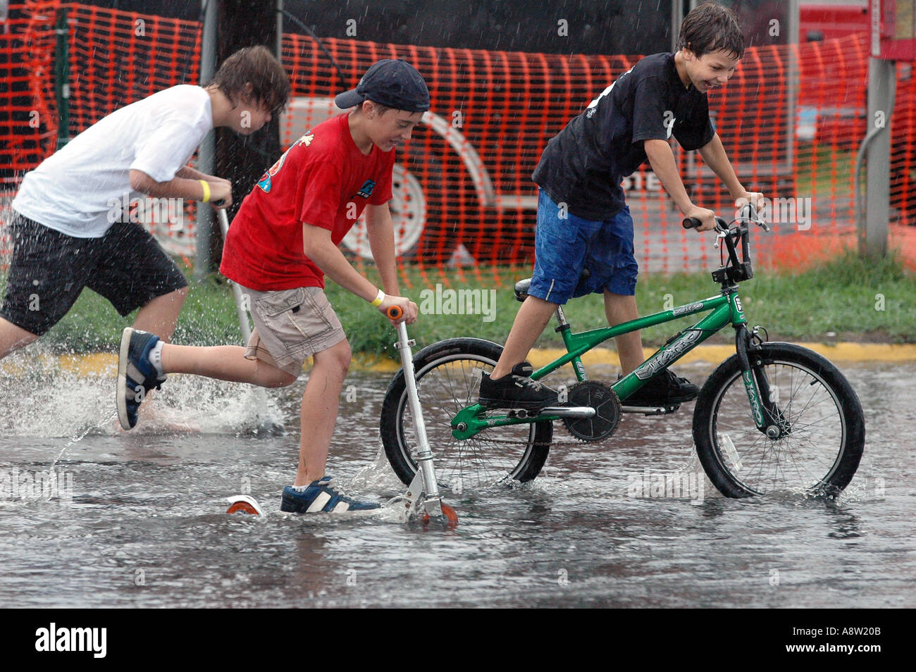 Kinder spielen auf der überfluteten Straße Reiten Fahrrad Fahrrad und Roller Stockfoto