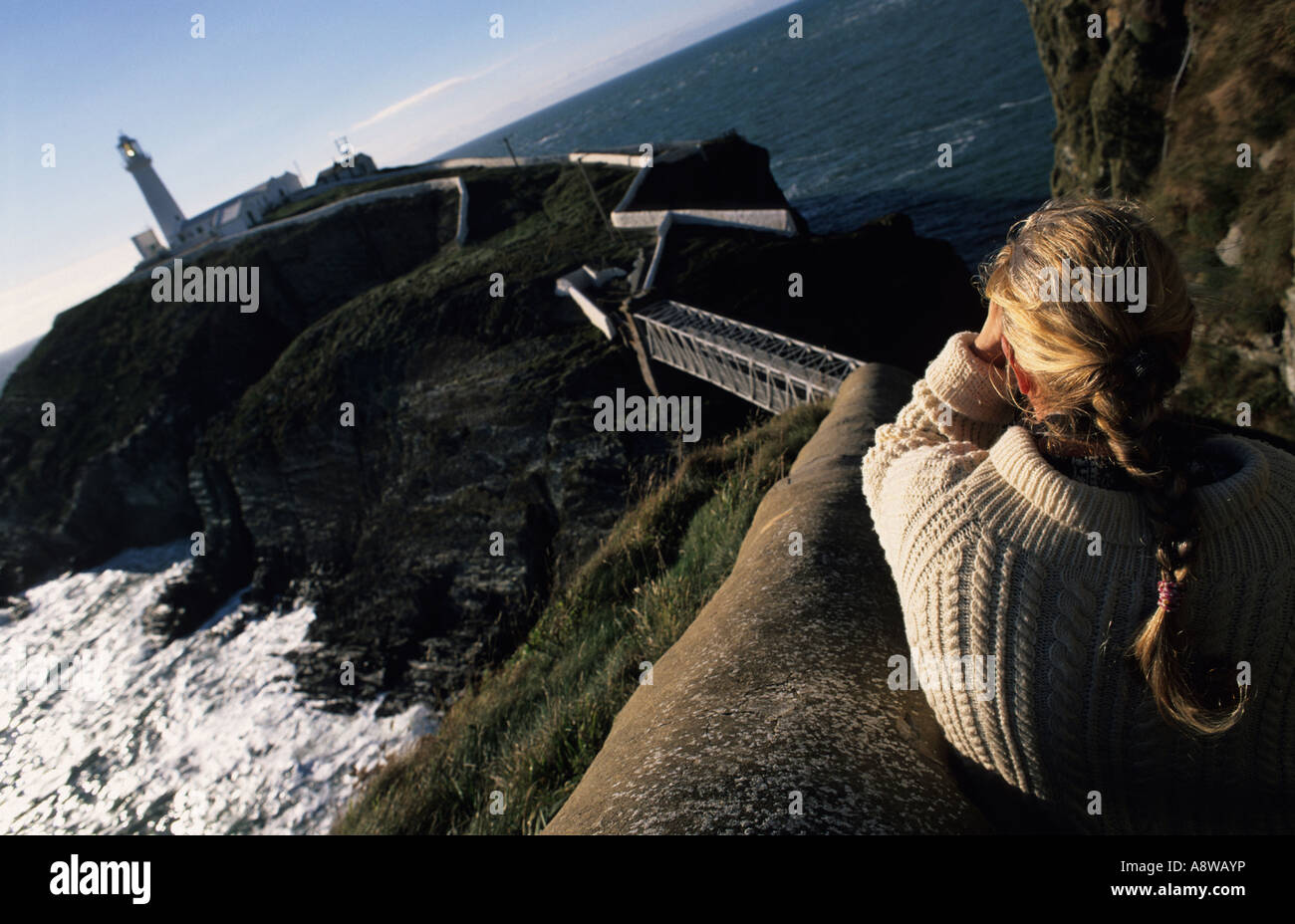 Frau in einer Aran-pullover und geflochtene Haar bei South Stack Lighthouse, Anglesey, North Wales, UK Stockfoto