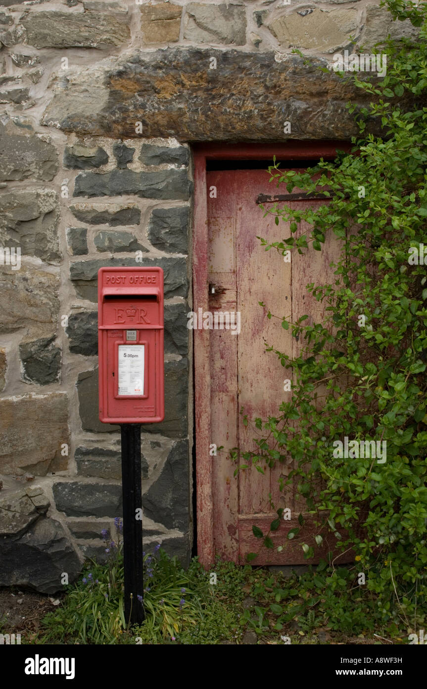 alten roten Briefkasten vor verblasst der alten gemalte rote Holztür Satz in Steinhaus Fassade ländlichen Nord-wales Stockfoto