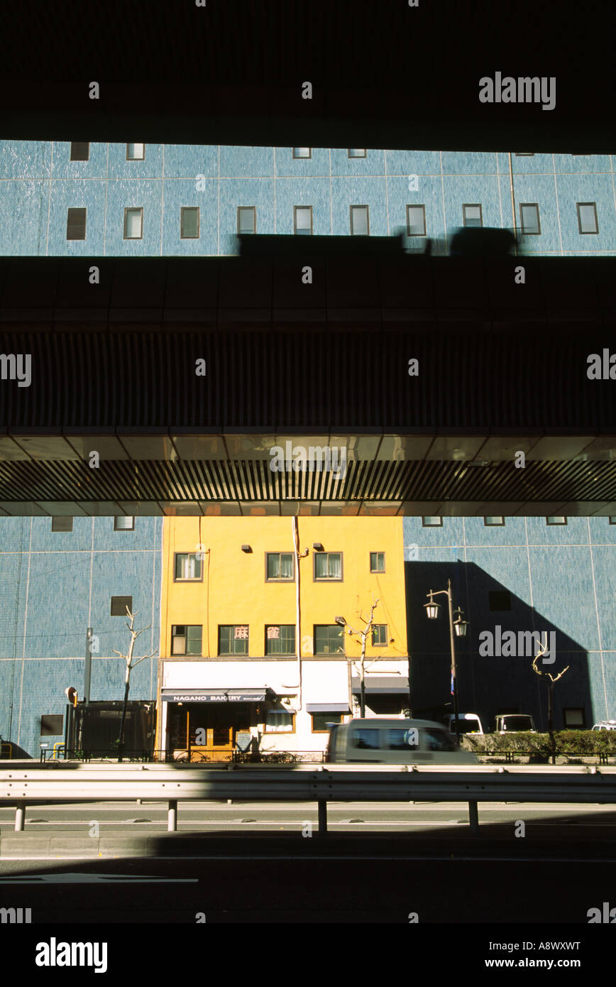 Schnellstraße Überführungen vor blau-gelben Gebäude in Tokio, Japan Stockfoto