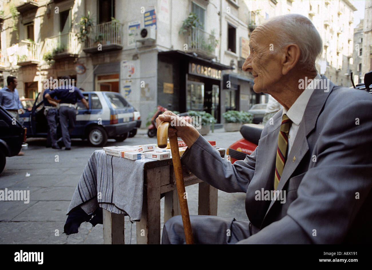 Napoli ein Alter Mann sitzt in der Altstadt von Orefici geschmuggelte Zigaretten in der Nähe ein Polizeiauto zu verkaufen Stockfoto