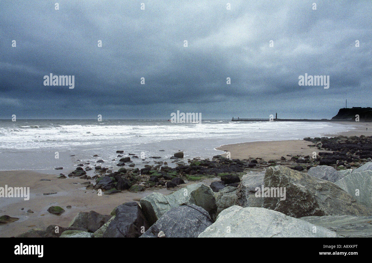 Dunklen Himmel raue See und Felsen, Whitby Sands, Whitby, North Yorkshire, England Stockfoto