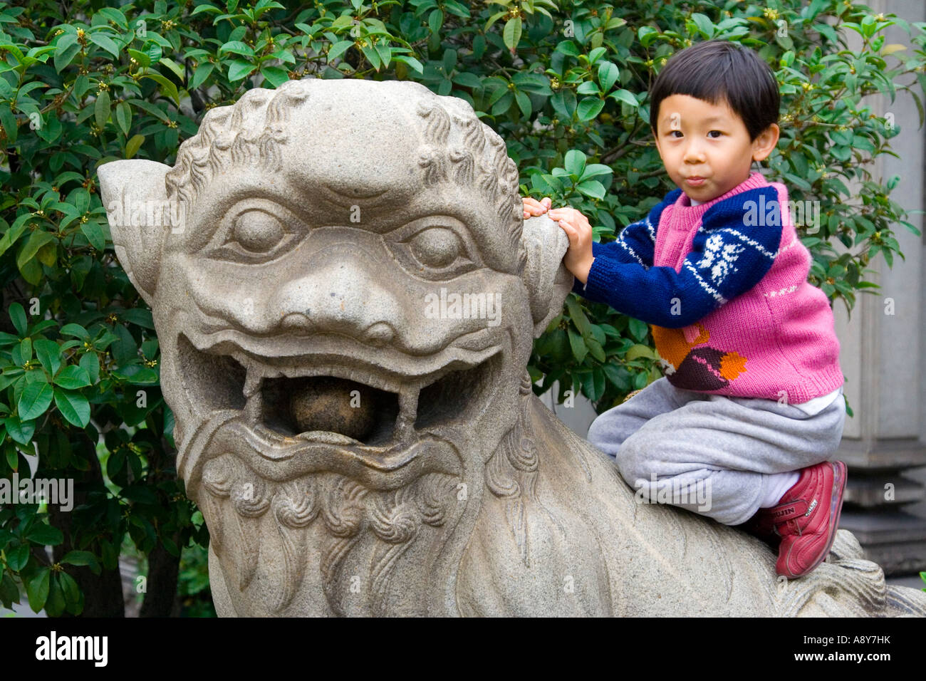 Kleiner Junge sitzt auf steinernen Löwen Statue Chen Clan Ahnenhalle Guangzhou China Stockfoto