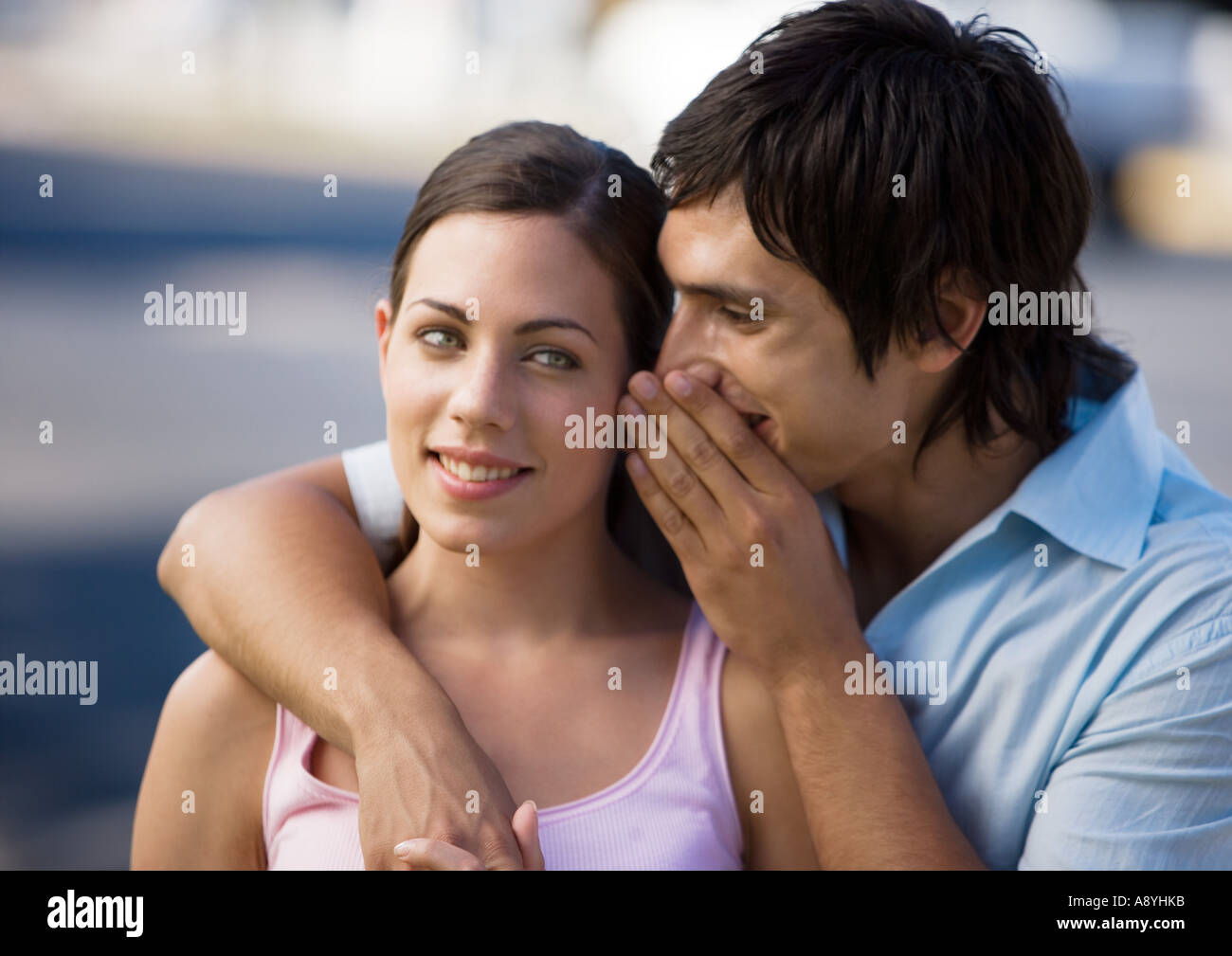 Junger Mann in Freundin Ohr flüstern Stockfoto