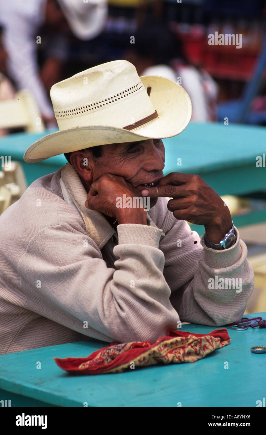 EIN CHAMULAN MAYA INDISCHER MANN SITZT AN EINEM BLAUEN TISCH AUF EINEM MARKT IN SAN JUAN CHAMULA CHIAPAS-MEXIKO Stockfoto