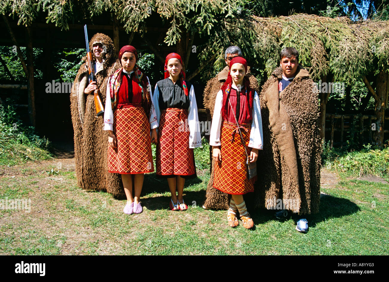Mädchen, gekleidet in bulgarische Tracht und Männer gekleidet als Jäger, Chalin Valog, Pirin-Gebirge in der Nähe von Bansko, Bulgarien Stockfoto