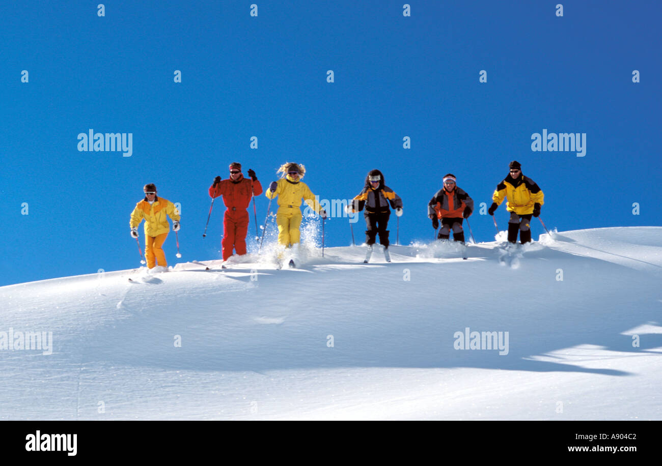 Gruppe von sechs Skifahrer in einer Linie Skifahren abseits der Piste über den Rand der Dicke Schnee Stockfoto
