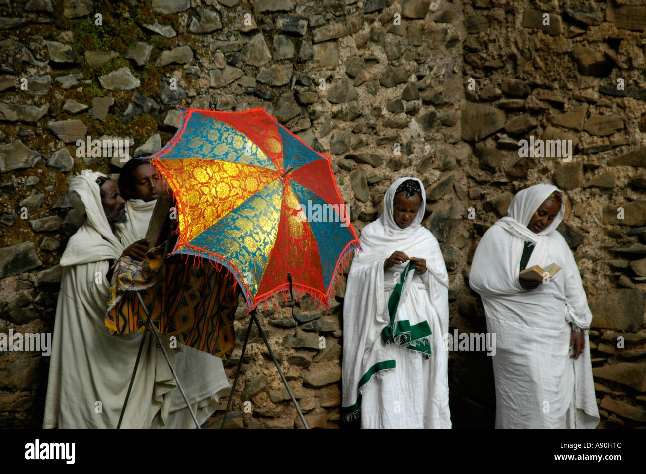 Christliche Gläubige stehend an einer Wand mit einer bunten Regenschirm Dreifaltigkeitskirche Debre Berhan Selassie Gondar Äthiopien Stockfoto
