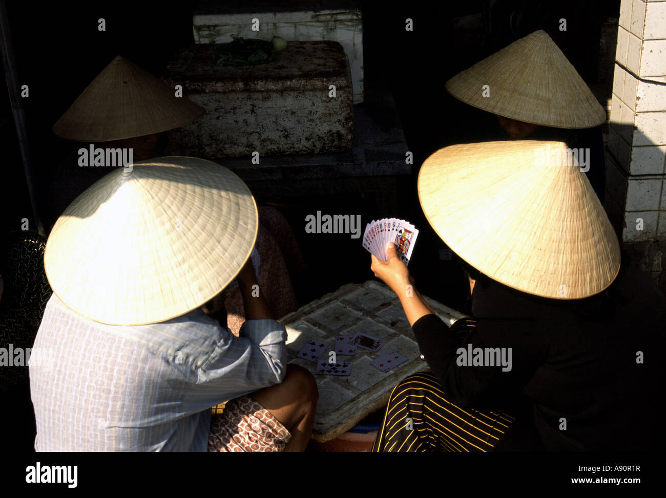 Farbfoto von Frauen, die Karten mit traditionellen Strohhüten spielen, Hoi-an, Vietnam, Asien Stockfoto