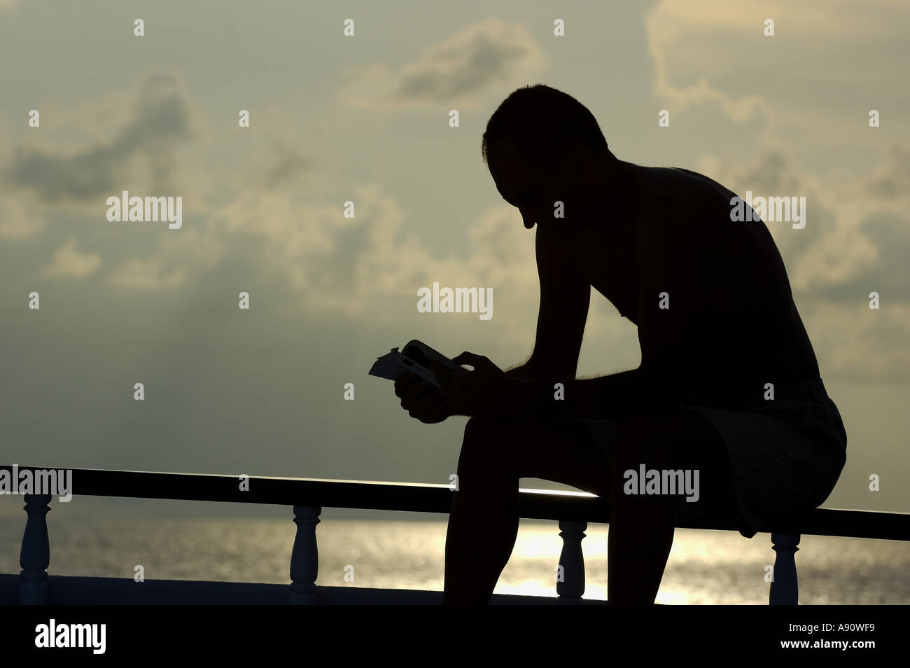 Silhouette eines Mannes im Urlaub ein Buch mit Blick auf den Ozean Stockfoto