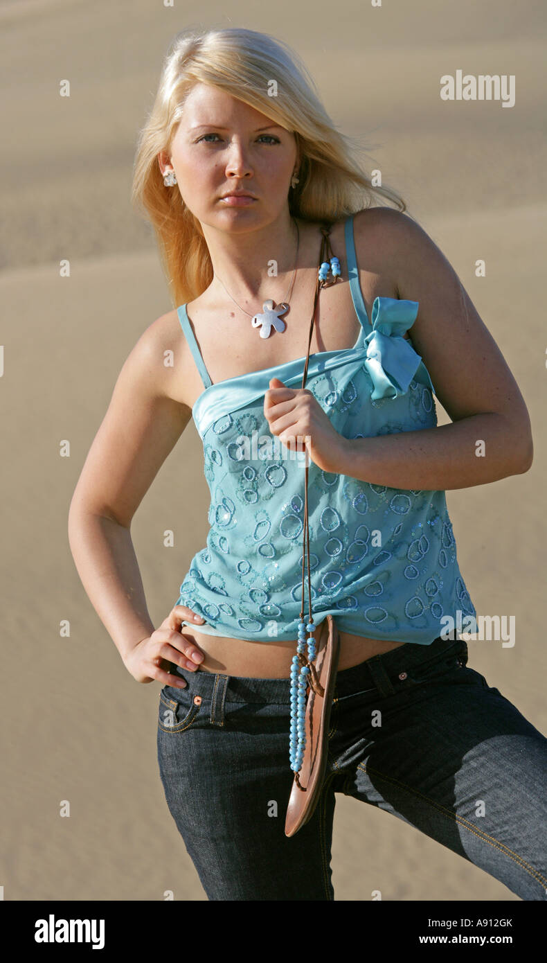 Blondes Mädchen mit einem blauen Oberteil und Jeans auf Sanddünen stehen Stockfoto