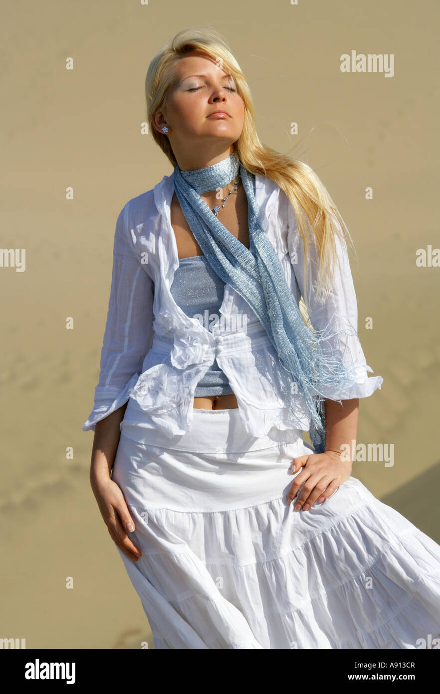 Blonde Mädchen mit blauen Top und weißen Hemd und Rock gegen Sanddünen Stockfoto
