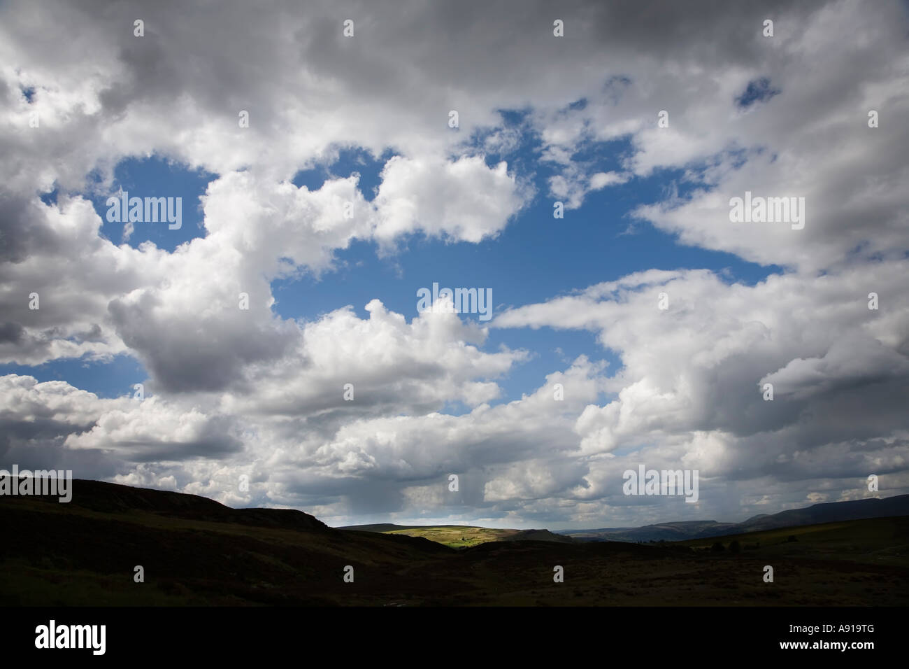 Entfernten Gebäude im Sonnenlicht mit dunklen Wolken sammeln Wales UK Stockfoto