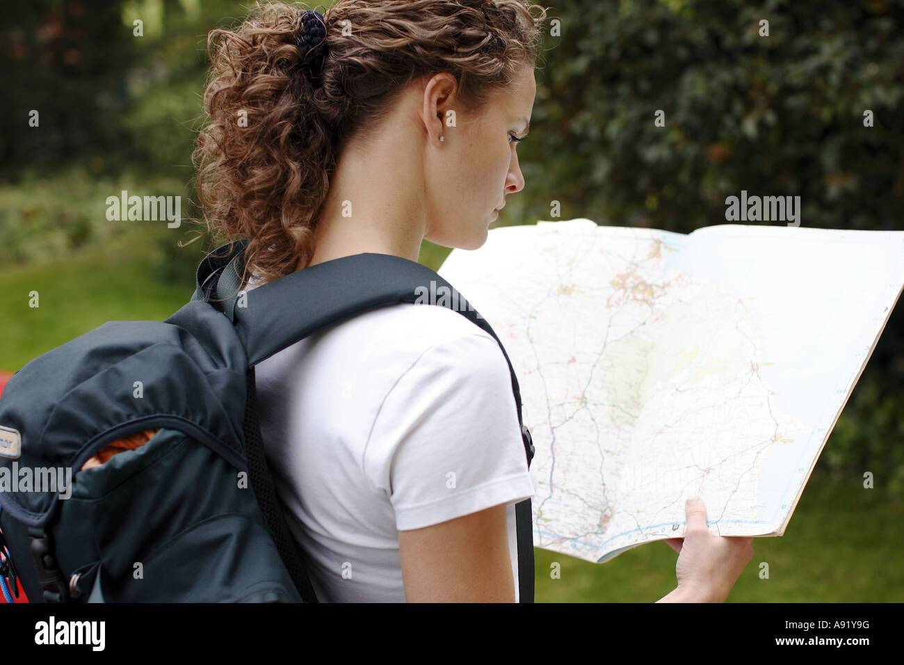 Mädchen auf der Suche auf einer Karte mit Rucksack auf dem Rücken Stockfoto
