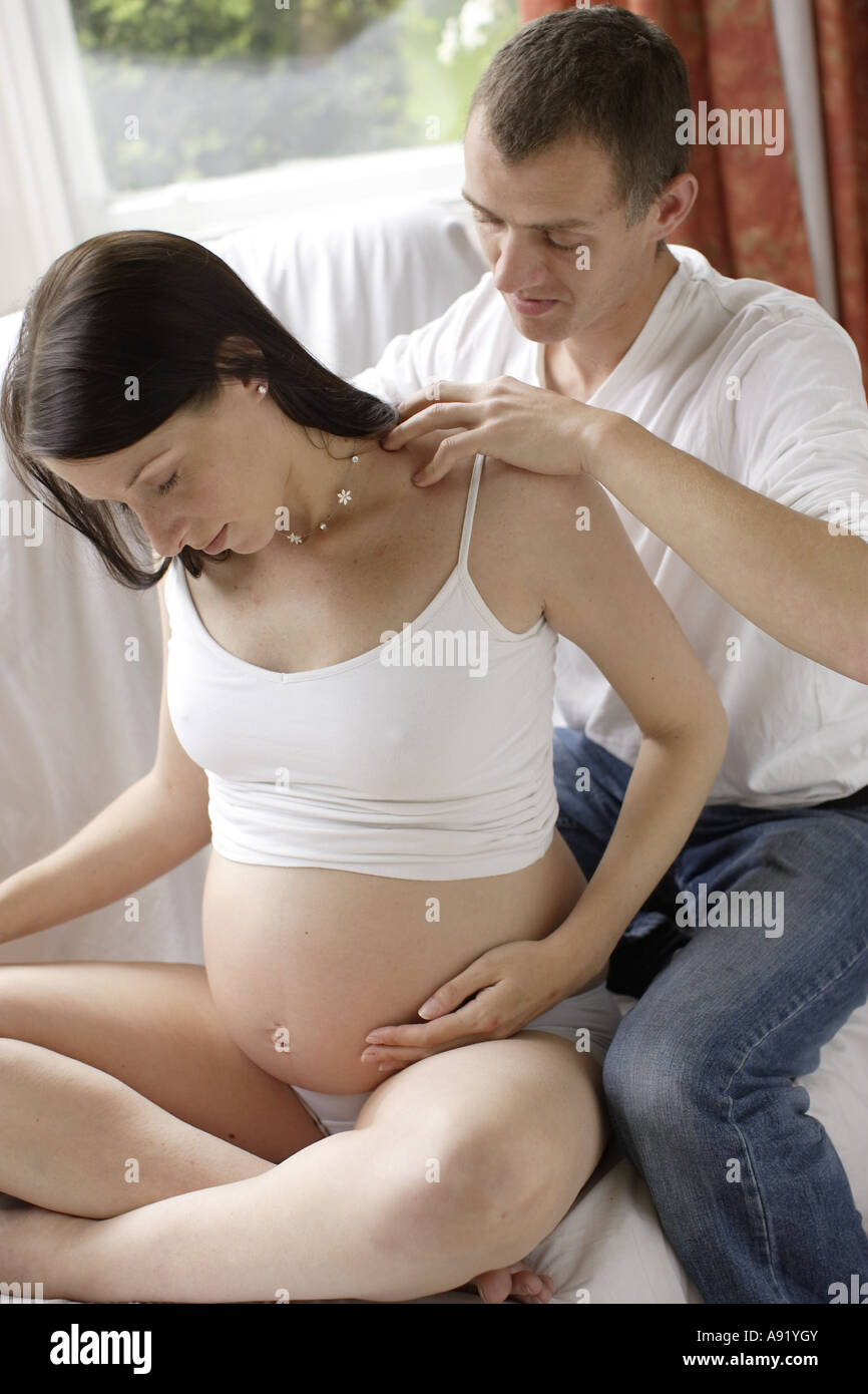 Schwangere Frau, die ihr wieder von ihrem Partner massiert Stockfoto